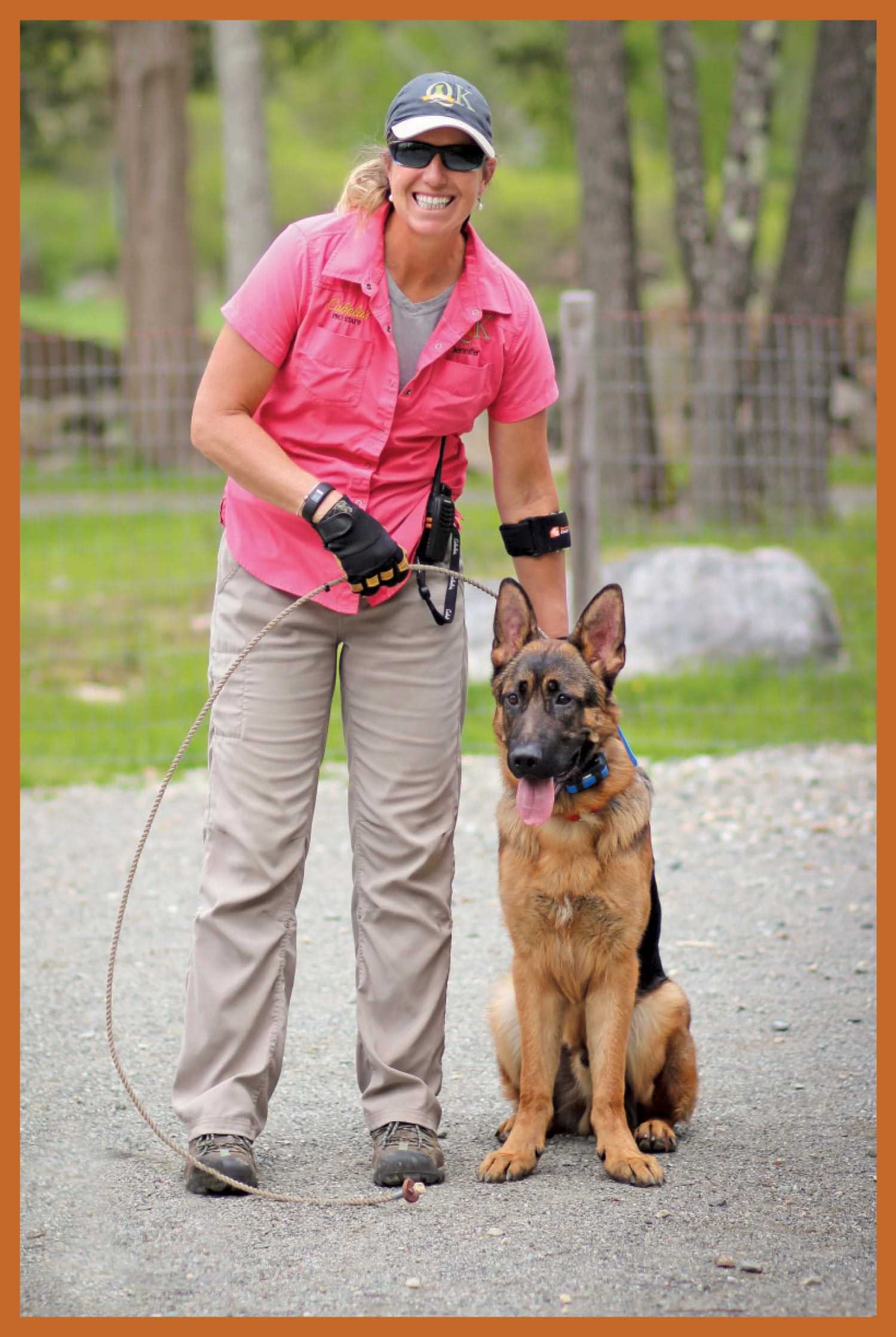 Jennifer Broome smiles holding the leash of a sitting German Shepard
