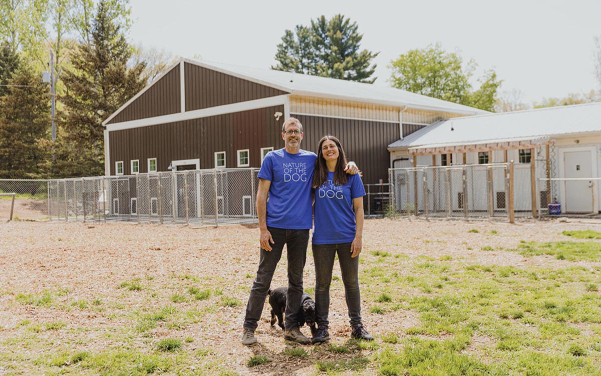 Luke and Jackie stand close together for a photo in front of their boarding and daycare facility, Nature of The Dog