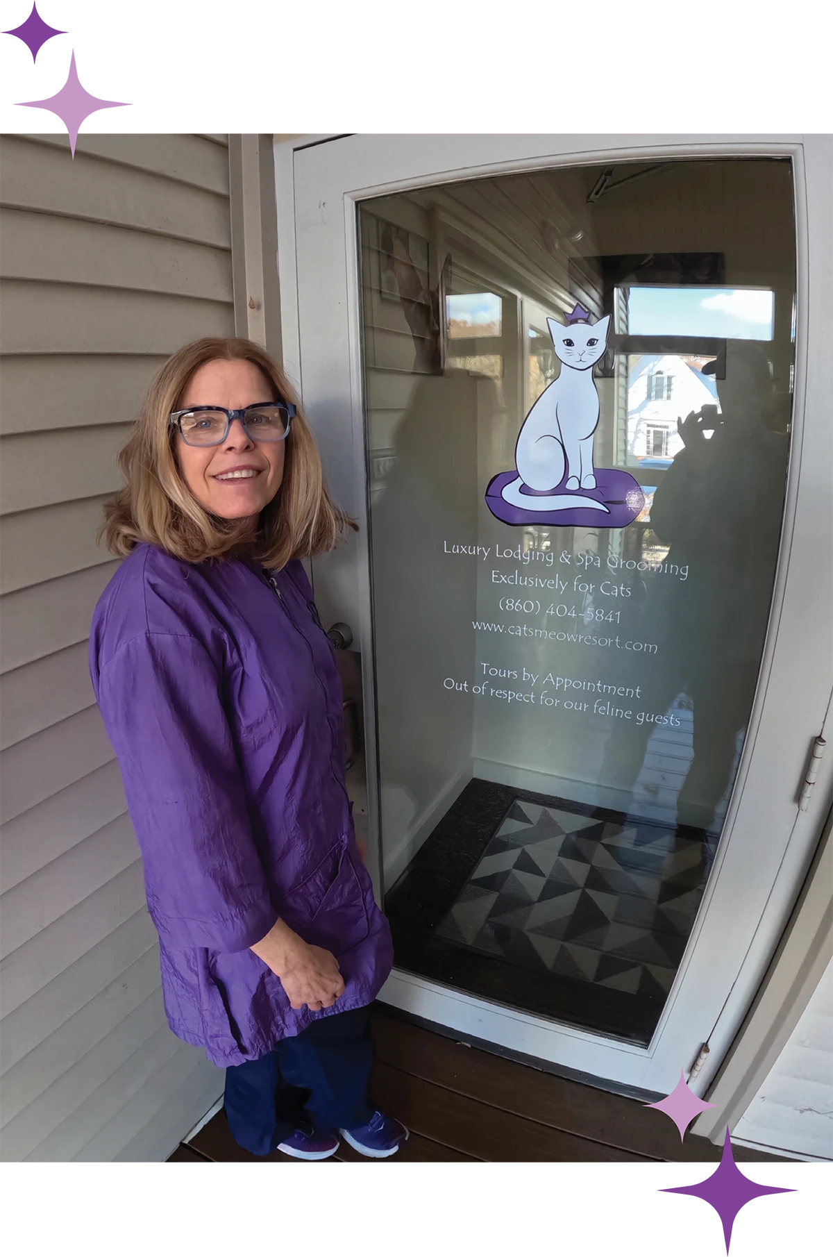 A woman with blonde hair and glasses wearing purple scrubs stands in front of a glass door for "The Cat's Meow Resort," a luxury cat lodging and spa.